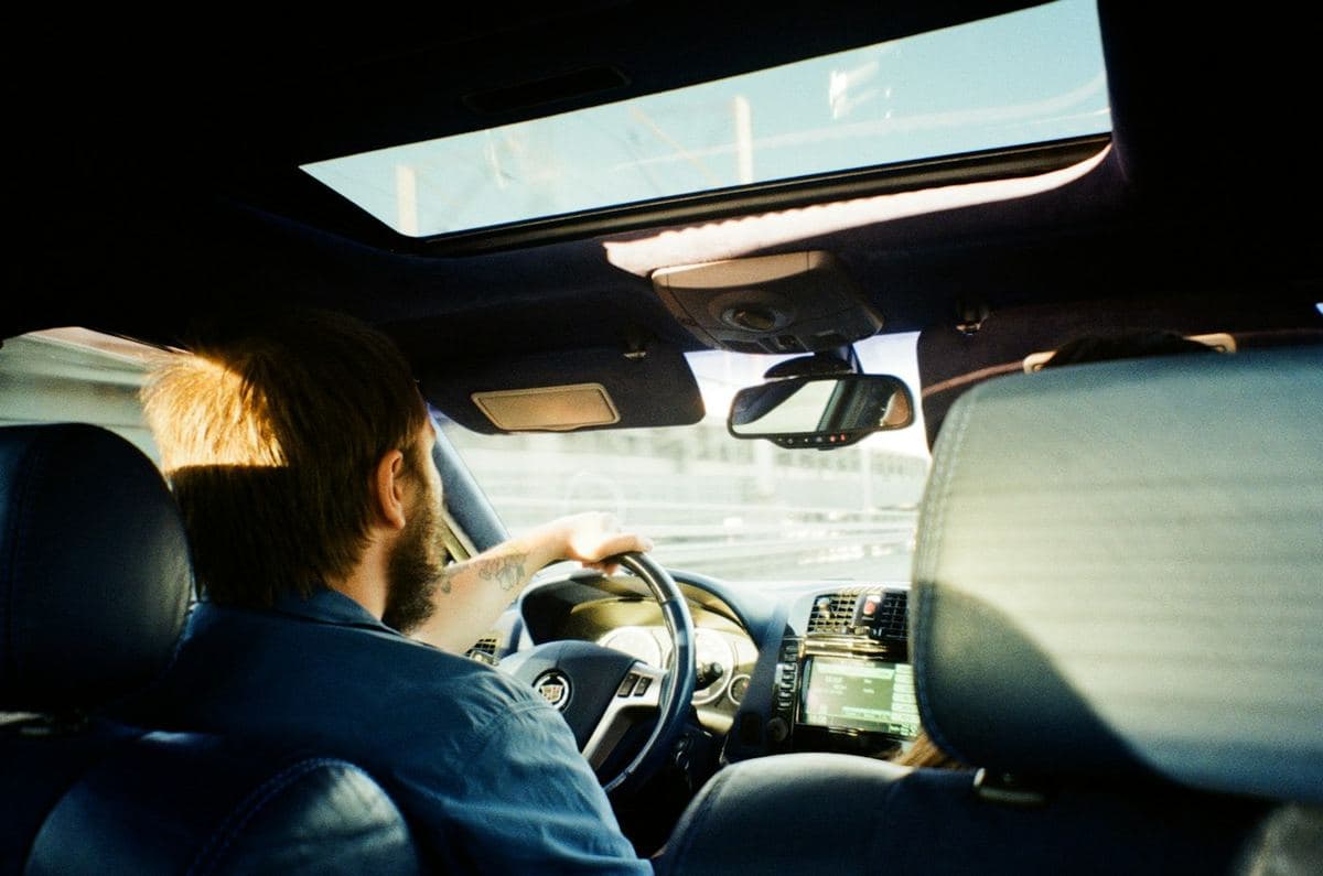 Motorista ao volante, visto de trás, com teto solar aberto
